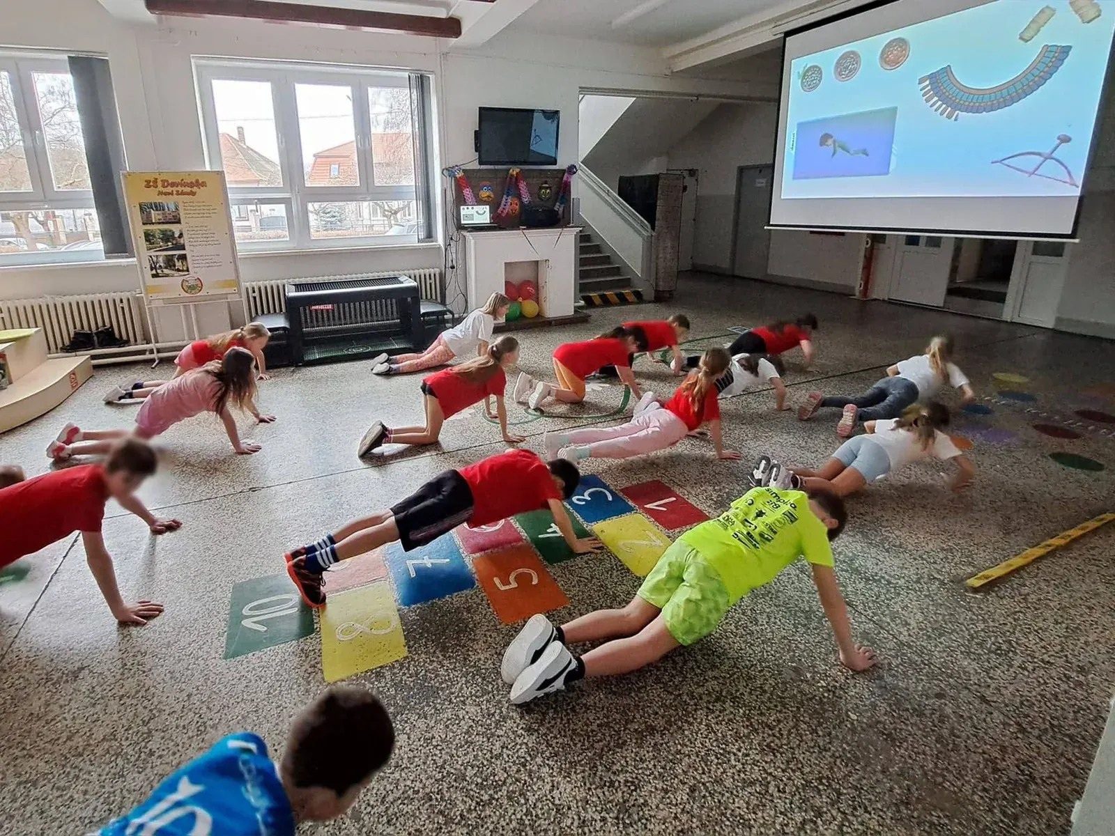 Trieda cvičí spolu podľa Paidorie premietanej na plátno